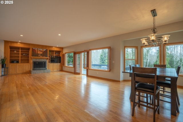 dining space featuring light wood-type flooring, baseboards, and an inviting chandelier