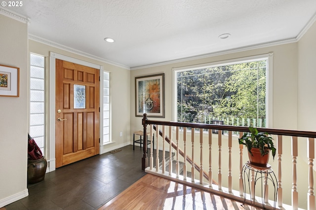 entryway with baseboards, a textured ceiling, and ornamental molding