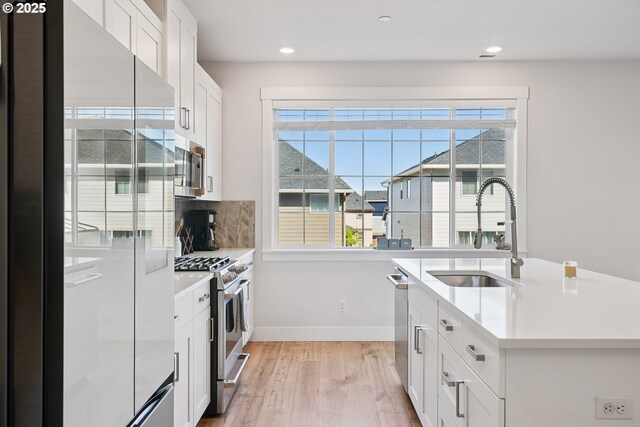 12545 SW Palermo St, Wilsonville, OR 97070 - kitchen featuring stainless steel appliances, a sink, baseboards, light wood-type flooring, and decorative backsplash