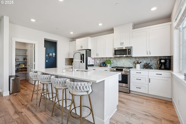 12545 SW Palermo St, Wilsonville, OR 97070 - kitchen with stainless steel appliances, light wood-style flooring, a sink, a kitchen island with sink, and recessed lighting