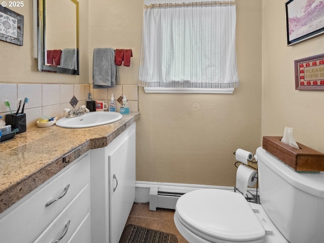 half bathroom with tile patterned floors, toilet, tasteful backsplash, baseboard heating, and vanity