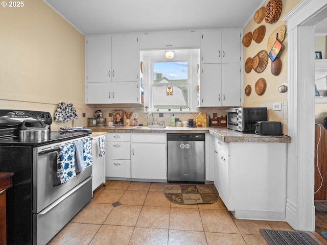 kitchen featuring light tile patterned flooring, a sink, stainless steel appliances, white cabinets, and tasteful backsplash