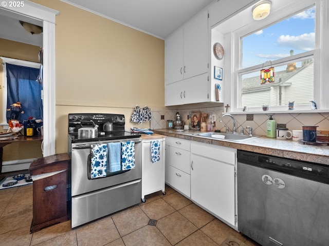 kitchen with light tile patterned floors, a sink, decorative backsplash, appliances with stainless steel finishes, and white cabinetry