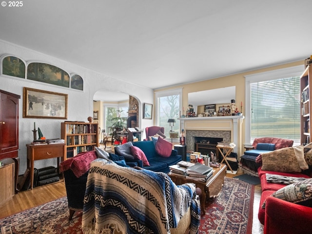 living room with a fireplace, wood finished floors, and arched walkways