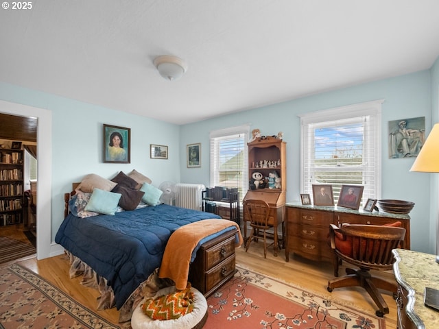 bedroom featuring radiator heating unit and light wood finished floors