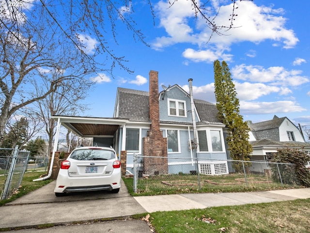 view of front facade with an attached carport, fence, roof with shingles, a chimney, and driveway