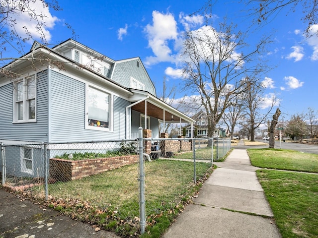 view of side of home featuring a fenced front yard, a gambrel roof, a lawn, and a gate