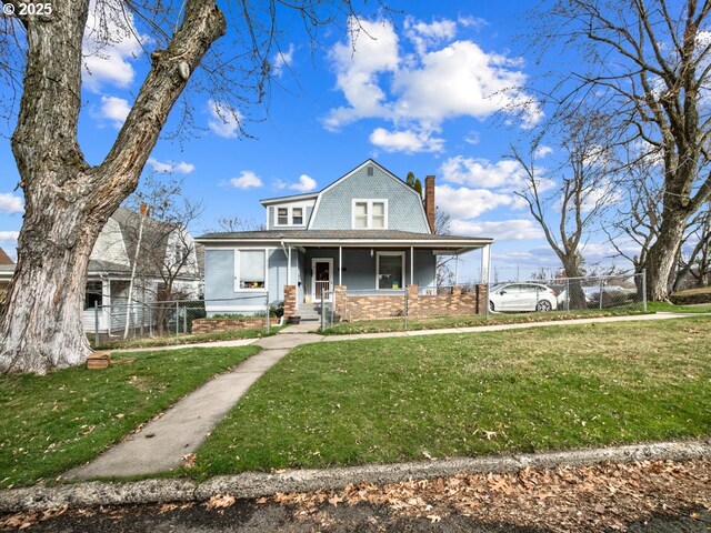 view of front of property with a gambrel roof, a porch, fence, a front yard, and a chimney