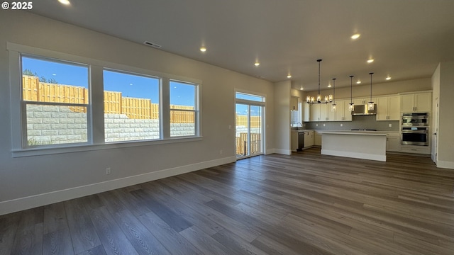unfurnished living room featuring recessed lighting, an inviting chandelier, baseboards, and visible vents