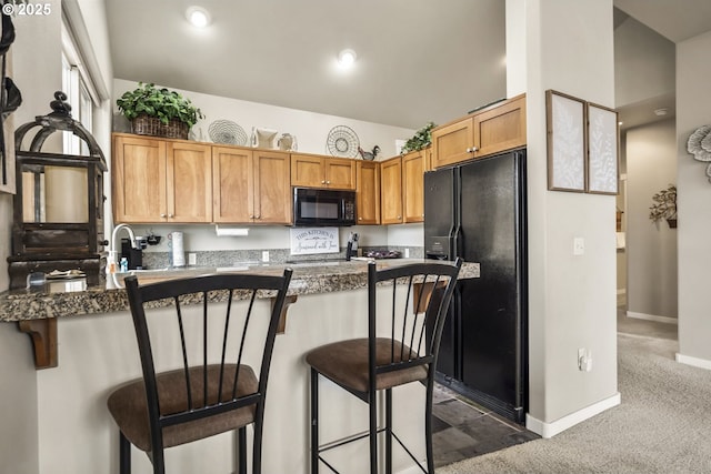 kitchen featuring dark colored carpet, kitchen peninsula, a kitchen breakfast bar, and black appliances