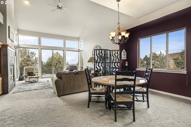 carpeted dining room with ceiling fan with notable chandelier and high vaulted ceiling