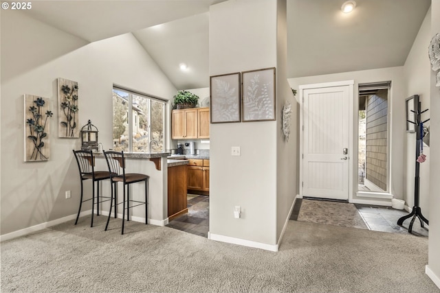 kitchen with lofted ceiling, dark carpet, a breakfast bar, and kitchen peninsula