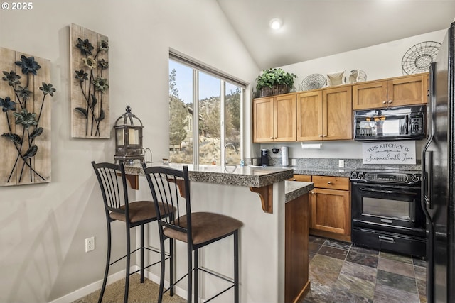 kitchen featuring vaulted ceiling, a breakfast bar, sink, and black appliances