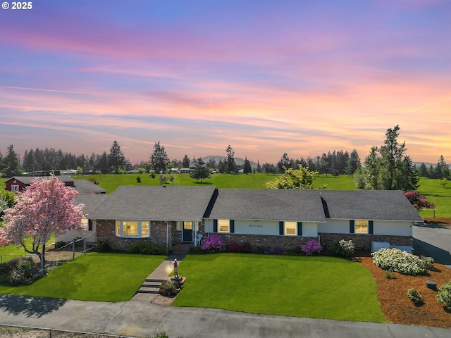 ranch-style home featuring brick siding, fence, and a front lawn