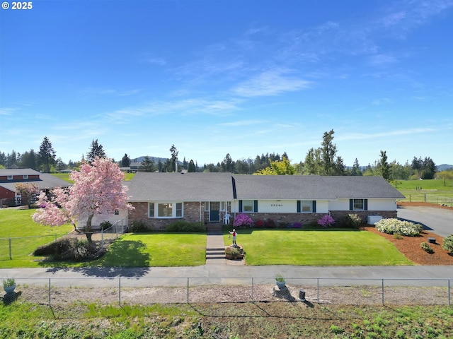 ranch-style house featuring fence, a front lawn, and brick siding