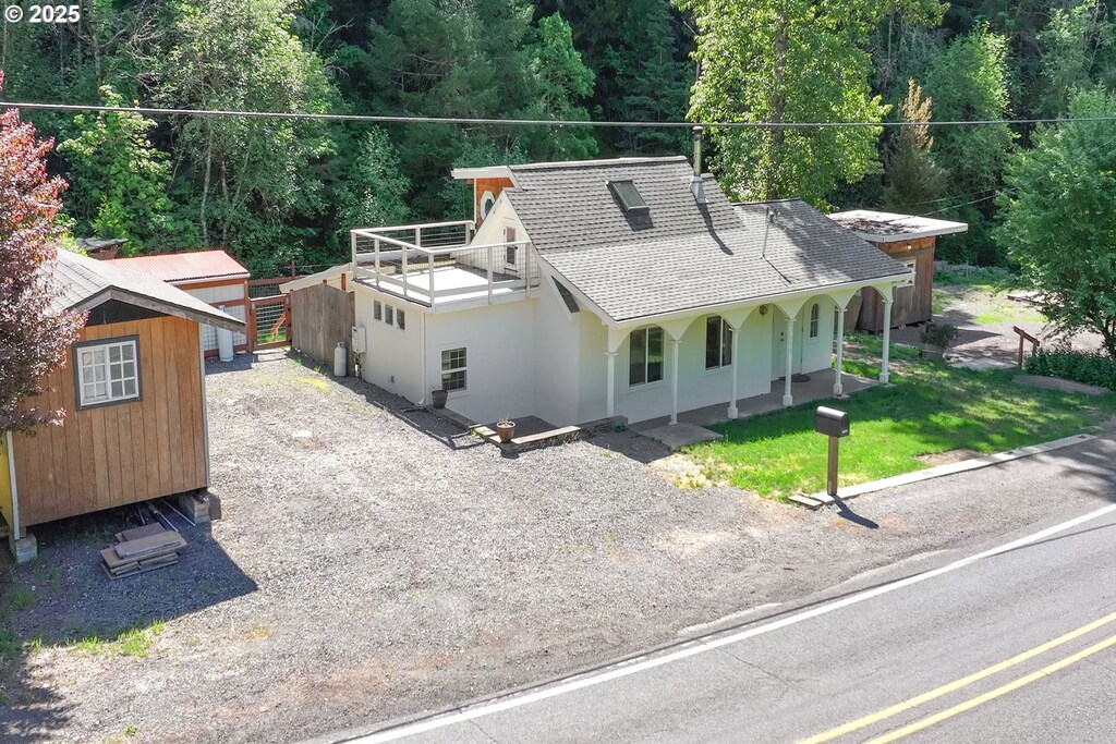 47938 Westoak Rd, Westfir, OR 97492 - view of front of home with roof with shingles, an outdoor structure, stucco siding, a porch, and a storage unit