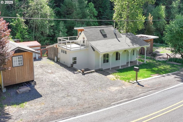 47938 Westoak Rd, Westfir, OR 97492 - view of front of home with roof with shingles, an outdoor structure, stucco siding, a porch, and a storage unit