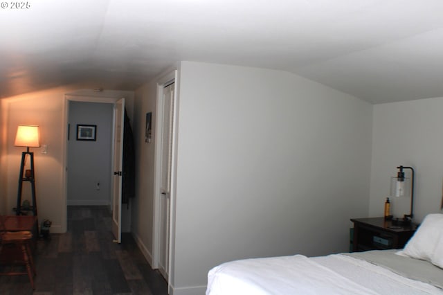 bedroom with baseboards, vaulted ceiling, and wood finished floors