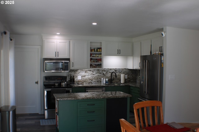 kitchen with white cabinets, dark wood-style floors, a sink, decorative backsplash, and appliances with stainless steel finishes
