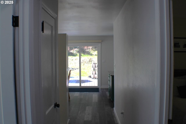 hallway featuring baseboards and dark wood-type flooring