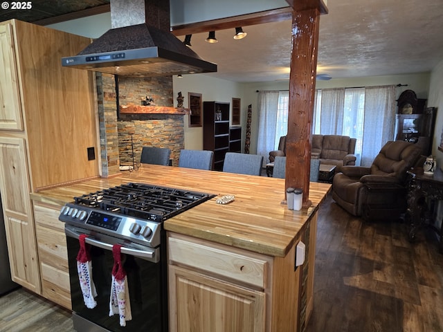 kitchen with light brown cabinetry, dark hardwood / wood-style flooring, stainless steel gas range oven, island range hood, and butcher block counters