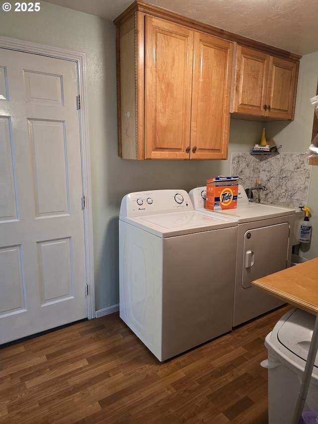 laundry area with cabinets, dark hardwood / wood-style floors, and washing machine and dryer