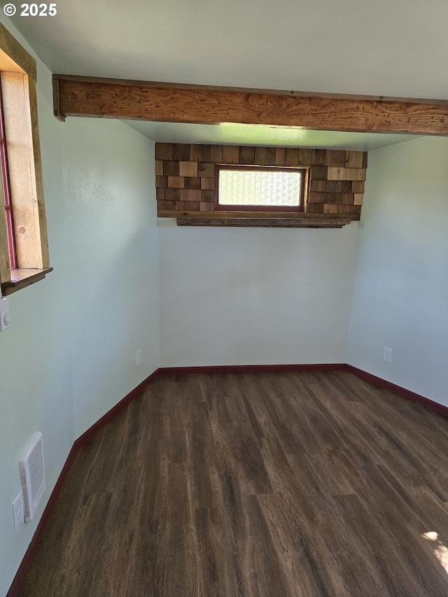 unfurnished room featuring beam ceiling and dark hardwood / wood-style floors