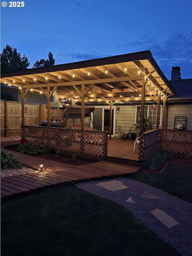 deck at dusk featuring a yard