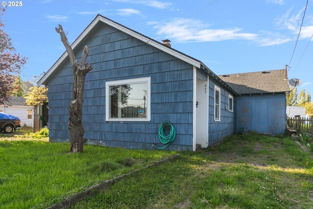 view of side of home with a lawn and fence
