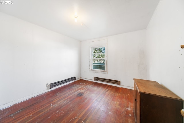spare room featuring a baseboard heating unit and hardwood / wood-style flooring