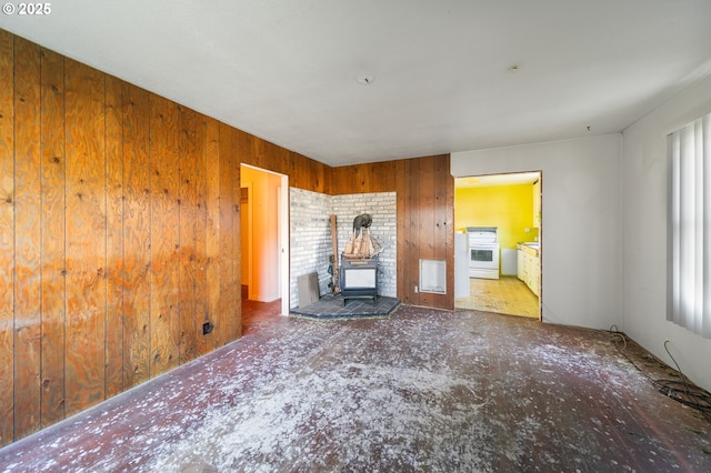 unfurnished living room featuring wooden walls and a wood stove