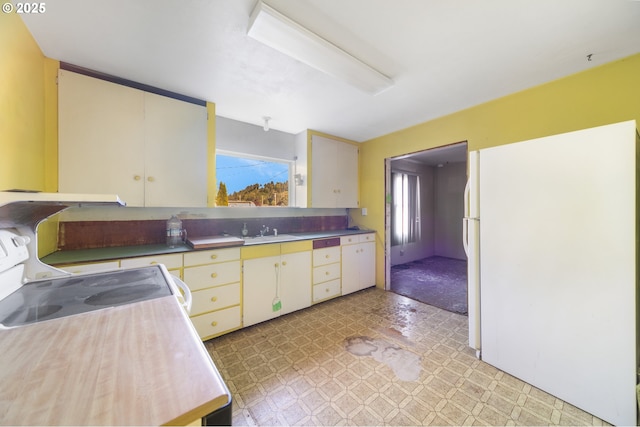 kitchen with cream cabinets, a wealth of natural light, freestanding refrigerator, and light floors
