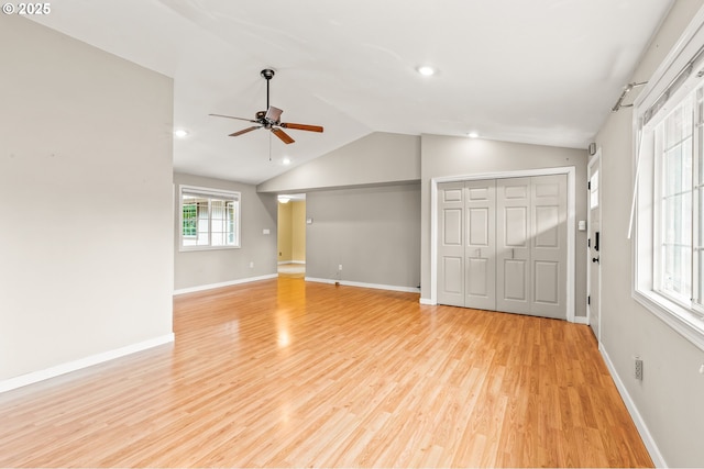 unfurnished living room with a ceiling fan, vaulted ceiling, baseboards, and light wood-type flooring