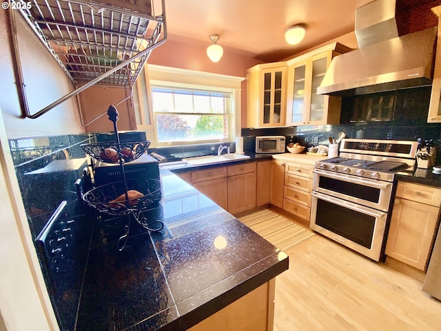 2083 NW Johnson St Unit 66, Portland, OR 97209 - kitchen with range with two ovens, white microwave, wall chimney exhaust hood, a sink, and light wood finished floors