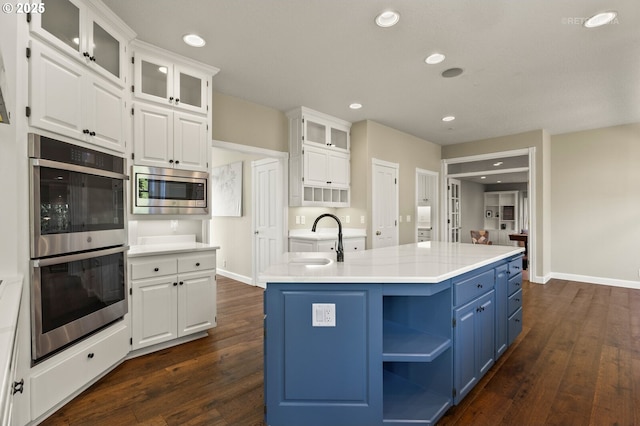 kitchen with stainless steel appliances, a sink, white cabinets, and blue cabinets