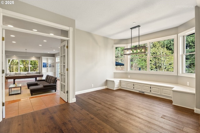 unfurnished dining area featuring recessed lighting, dark wood finished floors, a textured ceiling, and baseboards