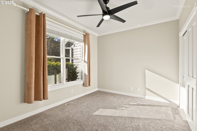 carpeted empty room featuring baseboards, ceiling fan, visible vents, and crown molding