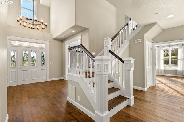 entrance foyer featuring a healthy amount of sunlight, a towering ceiling, baseboards, and hardwood / wood-style floors