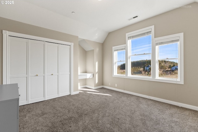 unfurnished bedroom with vaulted ceiling, carpet floors, multiple windows, and visible vents