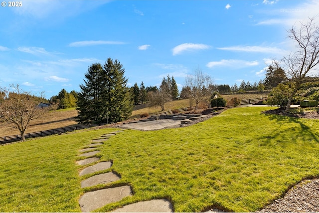 view of yard featuring a rural view, fence, and a patio