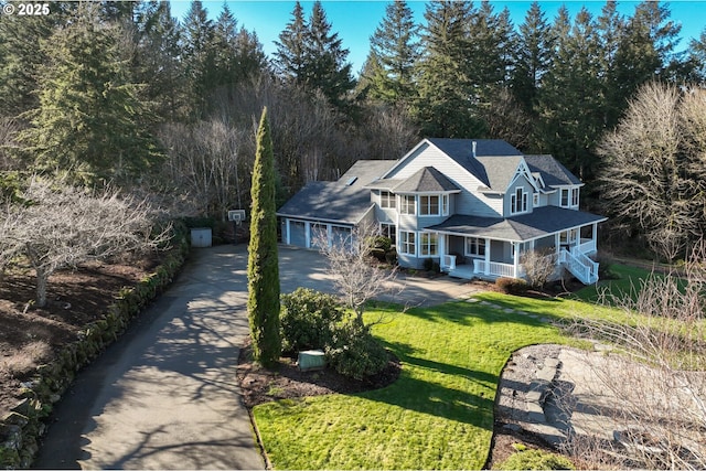 view of front of home with cooling unit, covered porch, driveway, and a front lawn