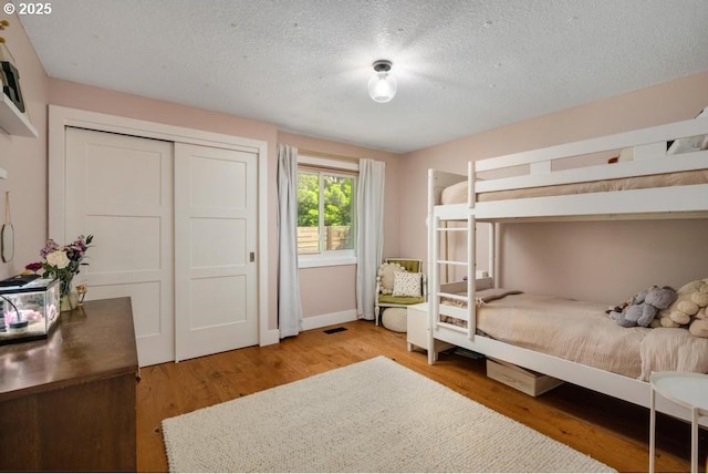 10701 SE Stevens Way, Happy Valley, OR 97086 - bedroom featuring wood finished floors, a textured ceiling, baseboards, and a closet