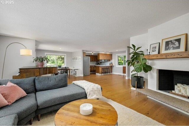 10701 SE Stevens Way, Happy Valley, OR 97086 - living room with a textured ceiling, light wood-style floors, plenty of natural light, a brick fireplace, and recessed lighting