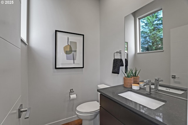 bathroom with toilet, vanity, and baseboards