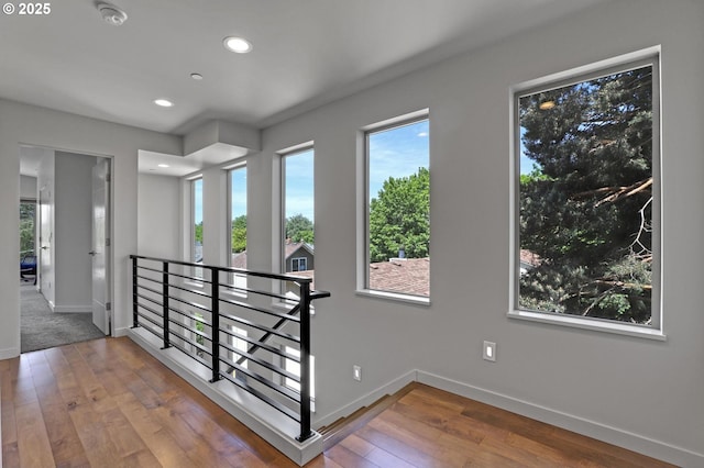 hall featuring an upstairs landing, baseboards, recessed lighting, and hardwood / wood-style flooring
