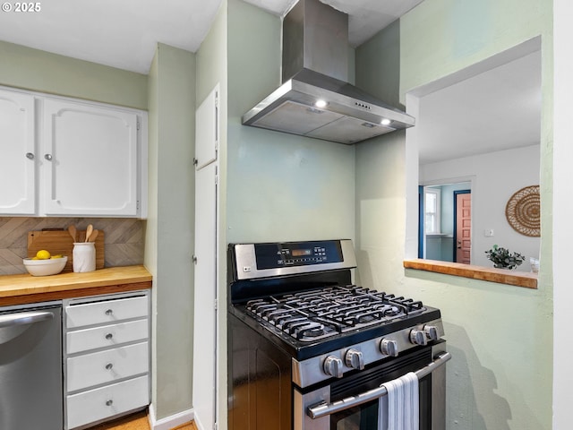 3516 N Missouri Ave, Portland, OR 97227 - kitchen featuring stainless steel appliances, wall chimney exhaust hood, white cabinets, tasteful backsplash, and butcher block countertops