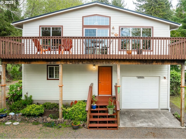 rear view of house featuring an attached garage, a deck, and concrete driveway