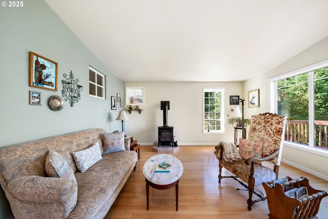 living room featuring light wood-style floors, baseboards, and a wood stove