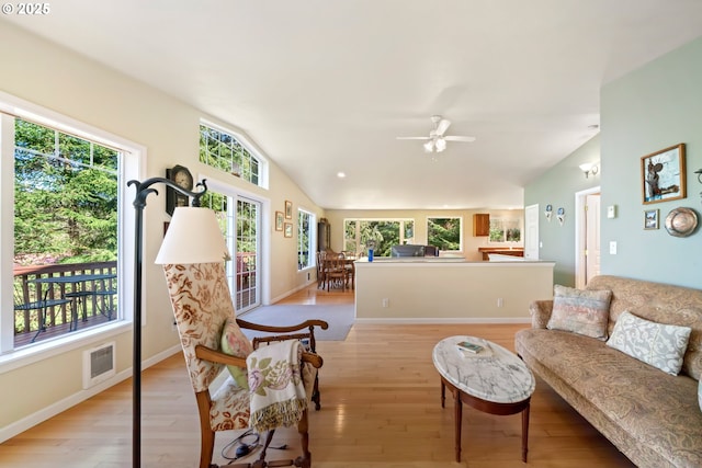 living area featuring visible vents, baseboards, ceiling fan, light wood finished floors, and vaulted ceiling