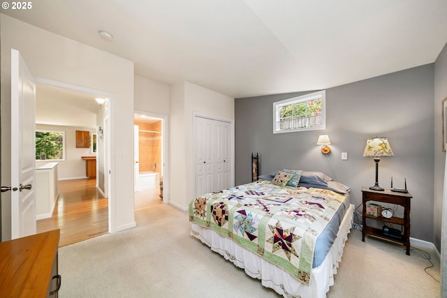 bedroom featuring baseboards, light colored carpet, multiple windows, and a closet
